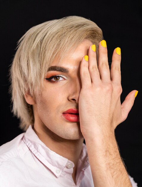 Mann, der Make-up trägt und seine Nägel gelb hat