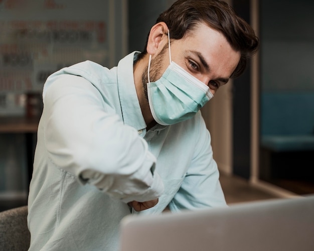 Mann, der medizinische Maske in einer Videokonferenz trägt