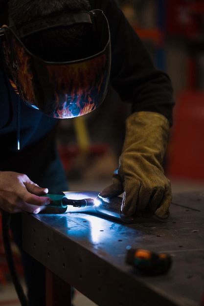 Mann, der mit einem Argon-Schweißgerät in einer Garage arbeitet