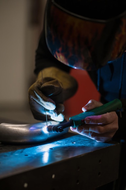 Mann, der mit einem Argon-Schweißgerät in einer Garage arbeitet