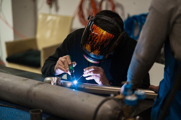 Mann, der mit einem Argon-Schweißgerät in einer Garage arbeitet