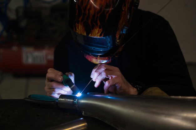 Mann, der mit einem Argon-Schweißgerät in einer Garage arbeitet