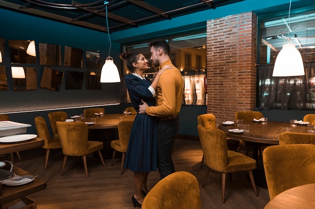 Kostenloses Foto mann, der mit fröhlicher frau im restaurant umarmt