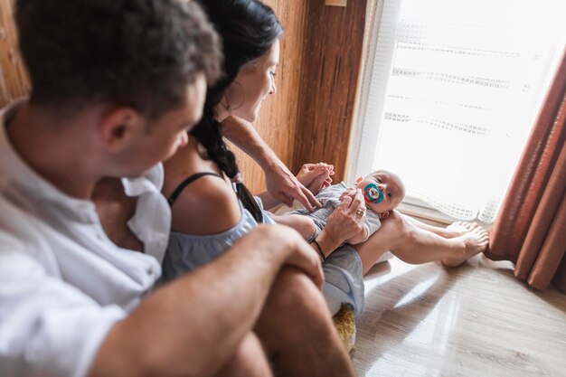 Mann, der mit ihrer Frau und Baby nahe dem Fenster sitzt