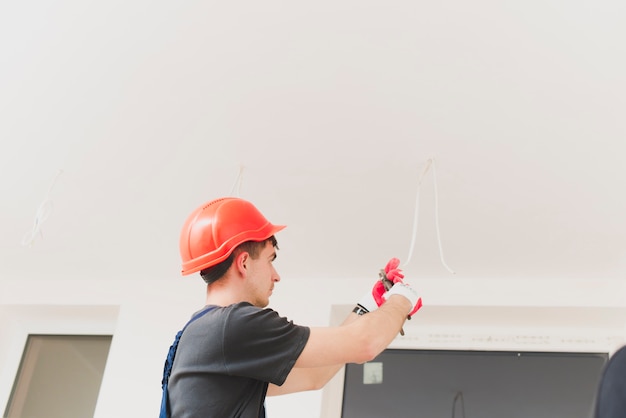 Kostenloses Foto mann, der mit kabeln an der decke arbeitet