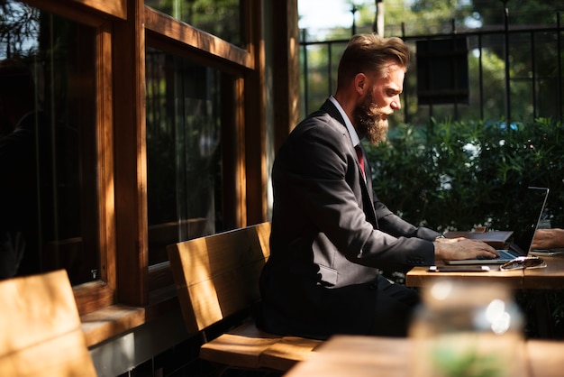 Mann, der mit Laptop an der Kaffeestube arbeitet