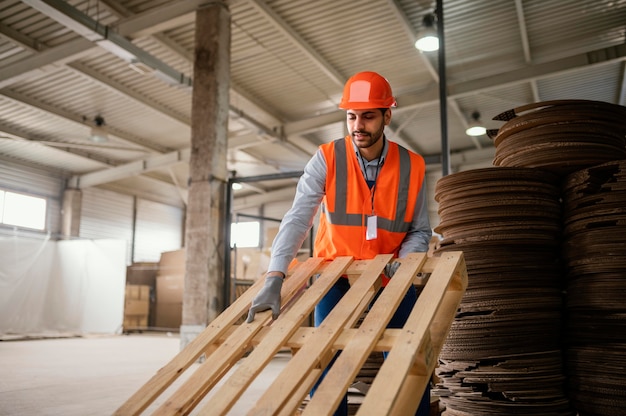 Mann, der mit schweren Holzmaterialien arbeitet