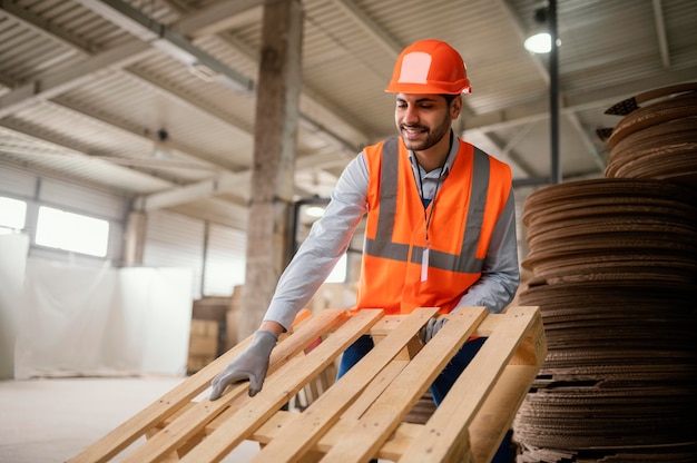 Kostenloses Foto mann, der mit schweren holzmaterialien arbeitet