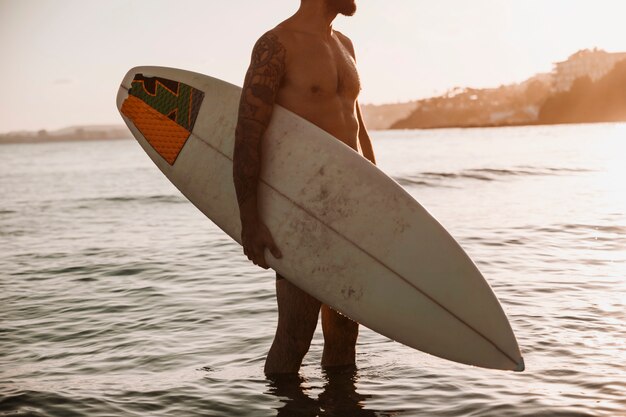 Mann, der mit Surfbrett im Meer steht