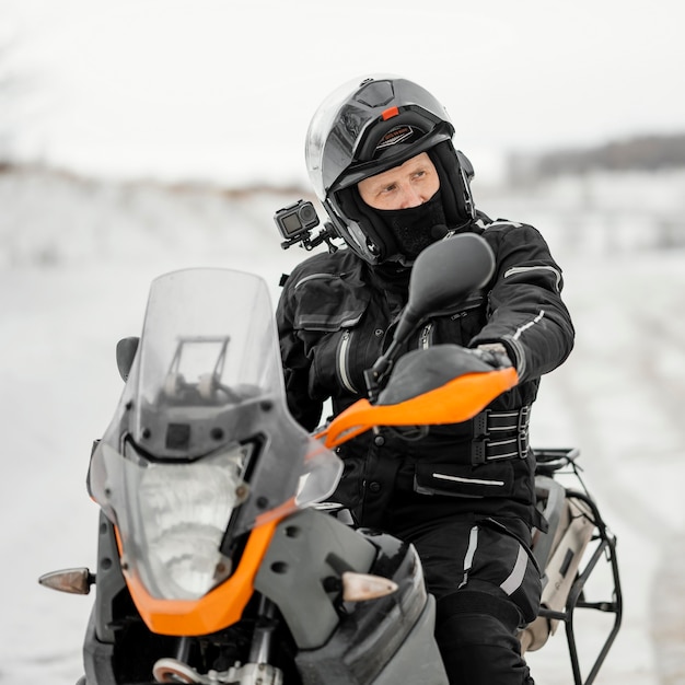 Mann, der Motorrad am Wintertag reitet