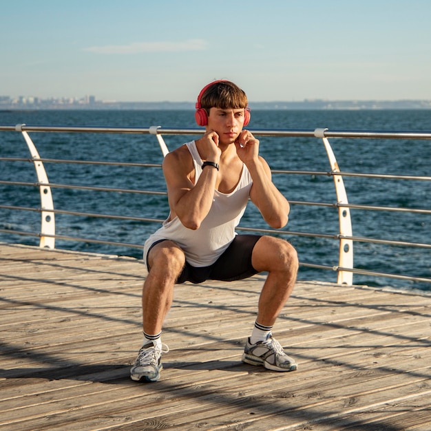 Mann, der Musik am Strand während des Trainings hört