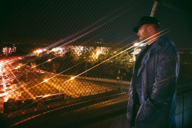Mann, der nachts auf der Brücke auf die belebte Stadtautobahn schaut