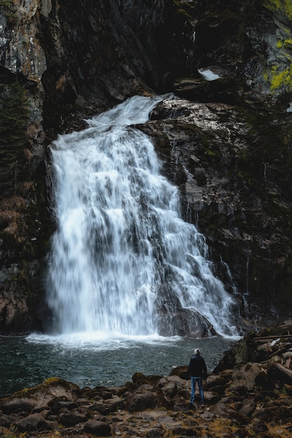 Mann, der nahe Wasserfällen steht