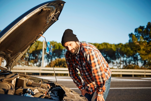 Kostenloses Foto mann, der neben seinem kaputten auto steht