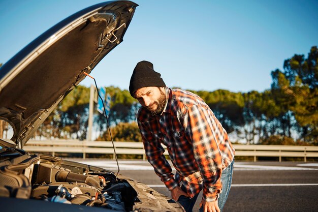 Mann, der neben seinem kaputten Auto steht