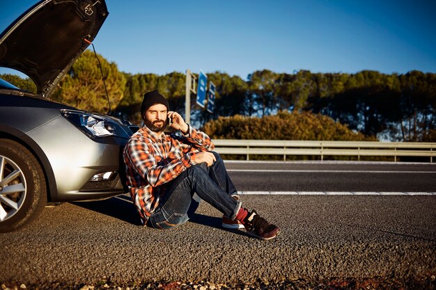 Mann, der neben seinem kaputten Auto steht