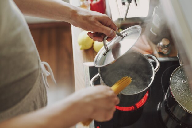 Mann, der Nudelspaghetti zu Hause in der Küche kocht.