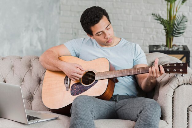 Mann, der online lernt, wie man Gitarre spielt