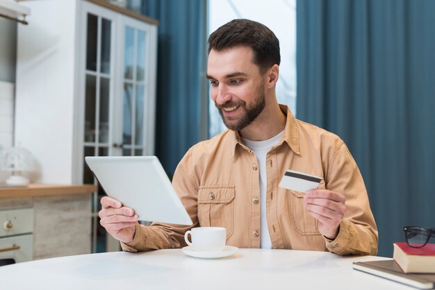 Mann, der online mit Tablette und Kreditkarte einkauft