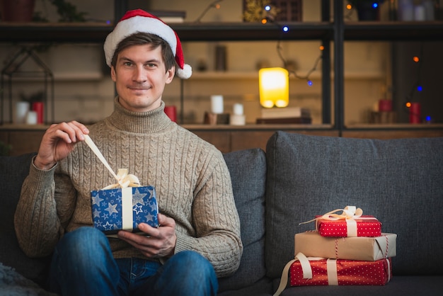 Kostenloses Foto mann, der sankt-hut öffnet blaues geschenk trägt