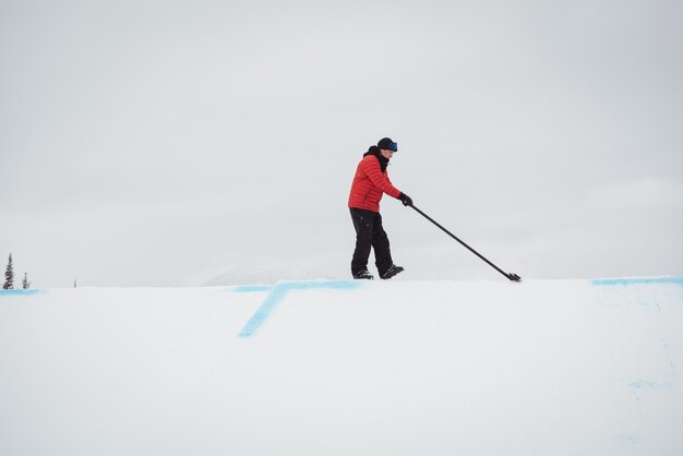 Mann, der Schnee im Skigebiet reinigt