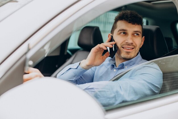 Mann, der sein Auto fährt und Handy benutzt