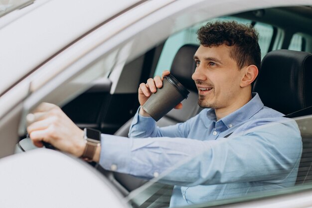 Mann, der sein Auto fährt und Kaffee trinkt