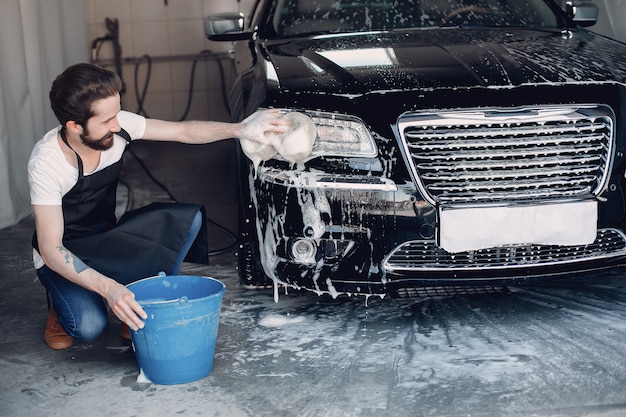 Mann, der sein Auto in einer Garage wäscht