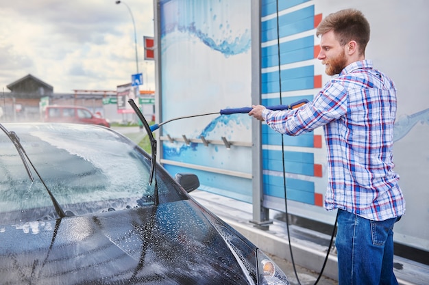 Kostenloses Foto mann, der sein auto in einer selbstbedienung putzt