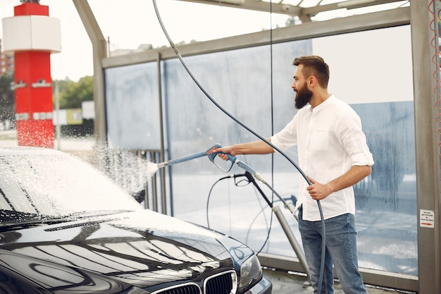 Mann, der sein Auto in einer Waschstation wäscht