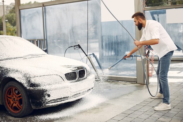 Mann, der sein Auto in einer Waschstation wäscht