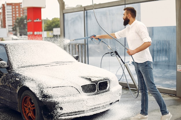 Mann, der sein Auto in einer Waschstation wäscht