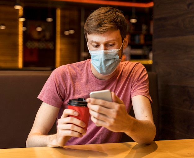 Mann, der sein Telefon in einem Café überprüft