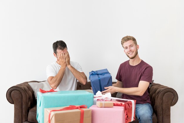 Mann, der seine schüchterne Freundgeschenkbox gegen weiße Wand gibt