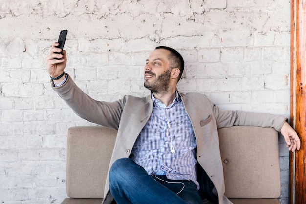 Kostenloses Foto mann, der selfie auf bank nimmt