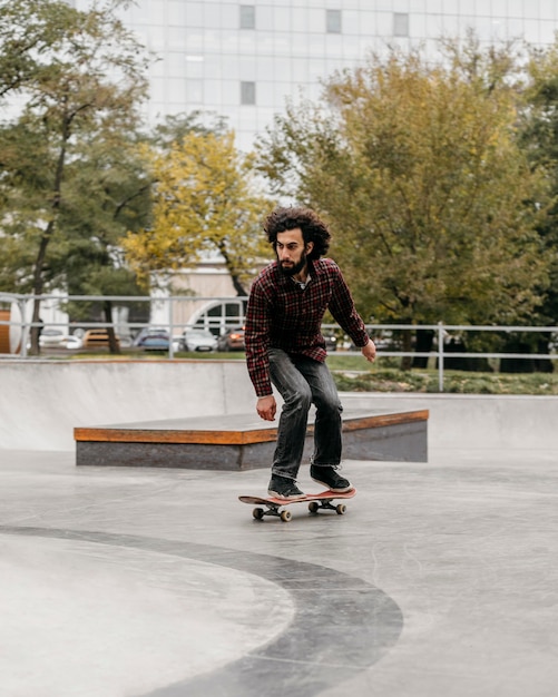 Kostenloses Foto mann, der skateboard draußen im park reitet