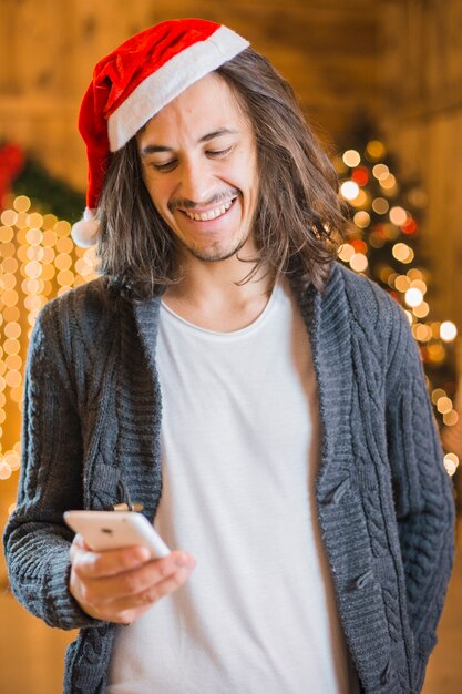 Mann, der Smartphone am Weihnachten betrachtet