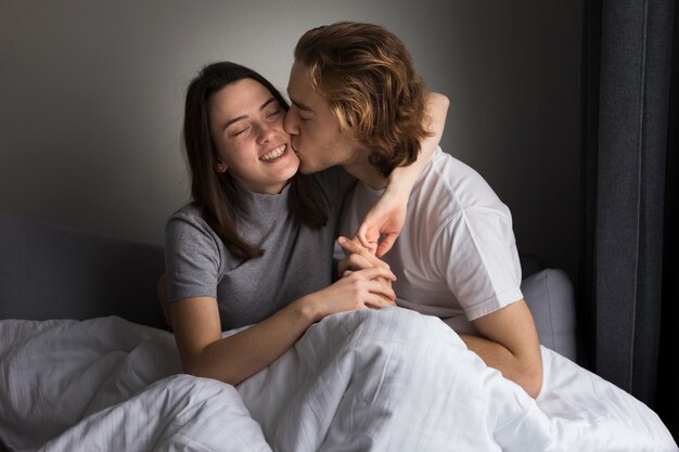 Mann, der smileyfreundin im Bett küsst