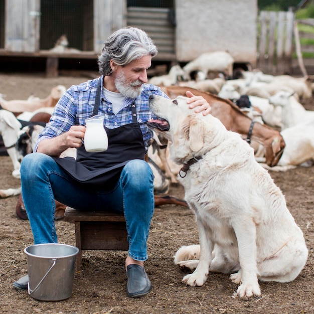 Mann, der Tasse Ziegenmilch hält und mit Hund spielt