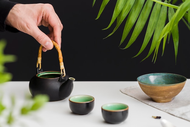 Mann, der Teetasse auf Tisch hält