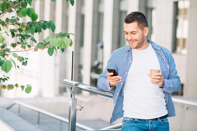 Mann, der Telefon nahe Geländer verwendet