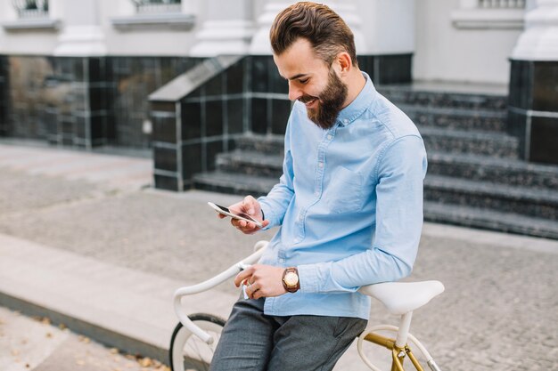 Mann, der Telefon verwendet und auf Fahrrad sich lehnt