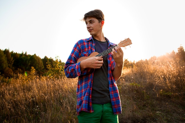 Kostenloses Foto mann, der ukulele spielt und weg schaut