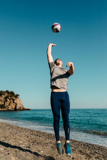 Mann, der Volleyball am Strand spielt