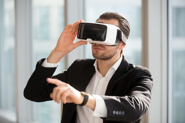 Mann, der VR-Kopfhörer trägt und auf die Luft zeigt