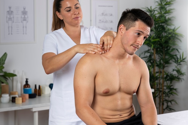 Kostenloses Foto mann, der während der physiotherapie-sitzung eine massage erhält