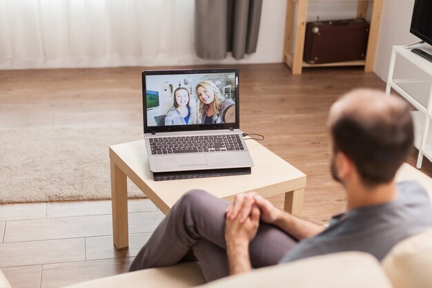 Mann, der während eines Videoanrufs in Zeiten der globalen Pandemie mit seiner Familie chattet.