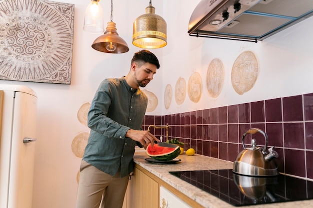 Kostenloses Foto mann, der wassermelone mittlerer schuss schneidet