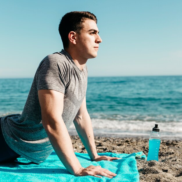 Mann, der Yoga am Strand tut