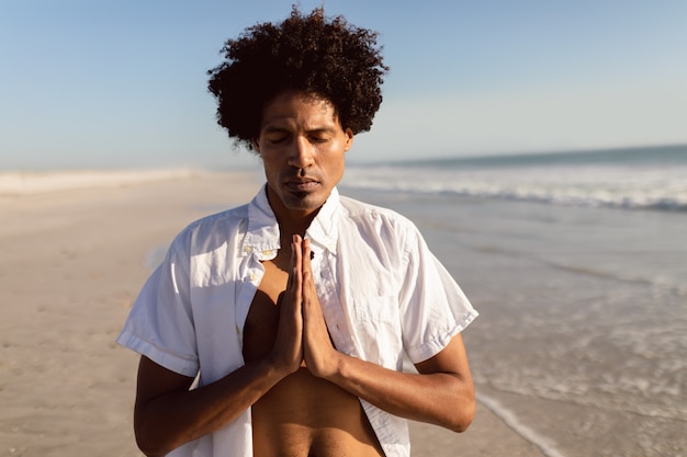 Mann, der Yoga auf dem Strand durchführt